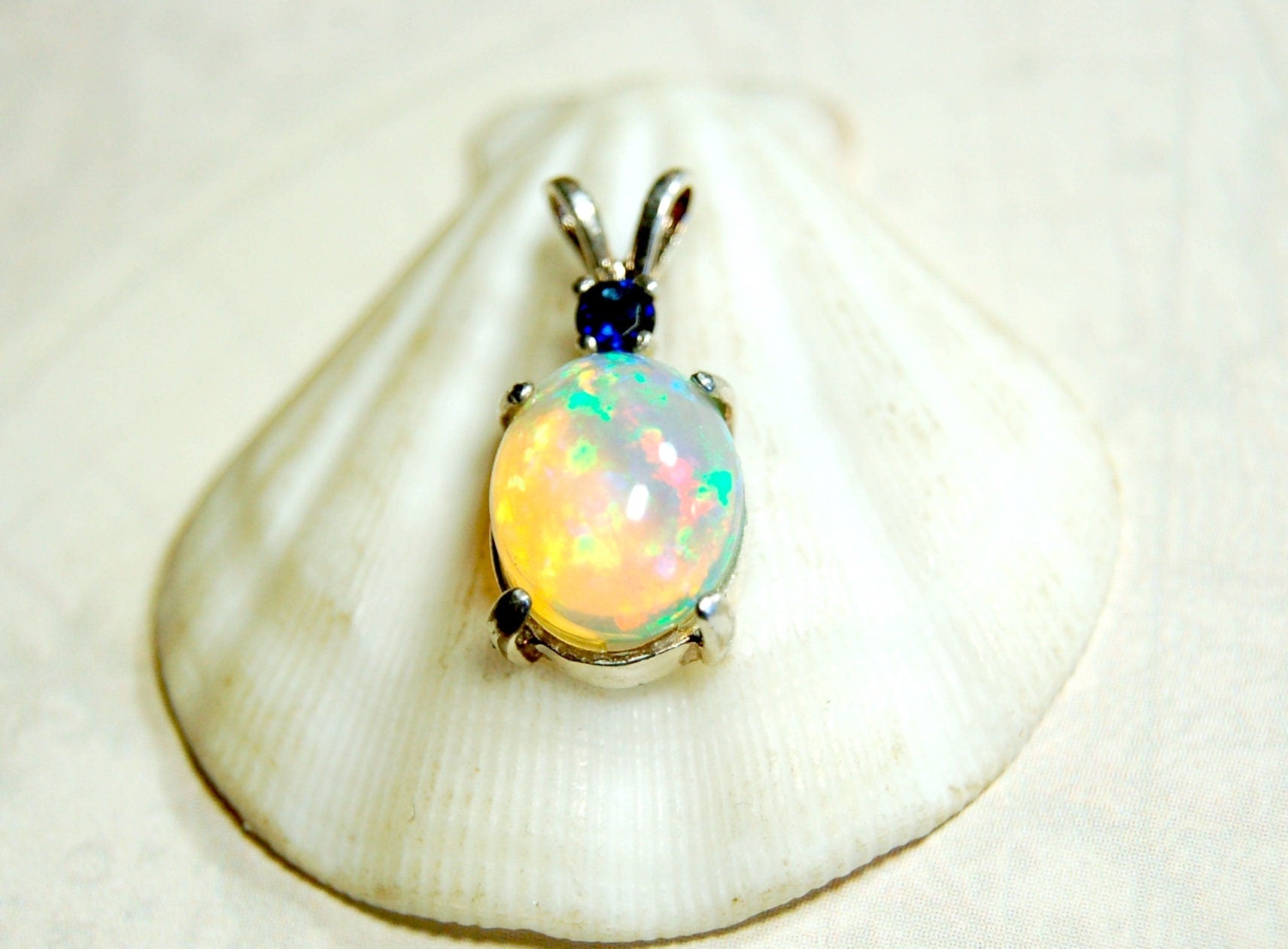 Natural opal pendant with blue sapphire.Good quality with many colors.The perfect gift.Must see video for true colors.042114