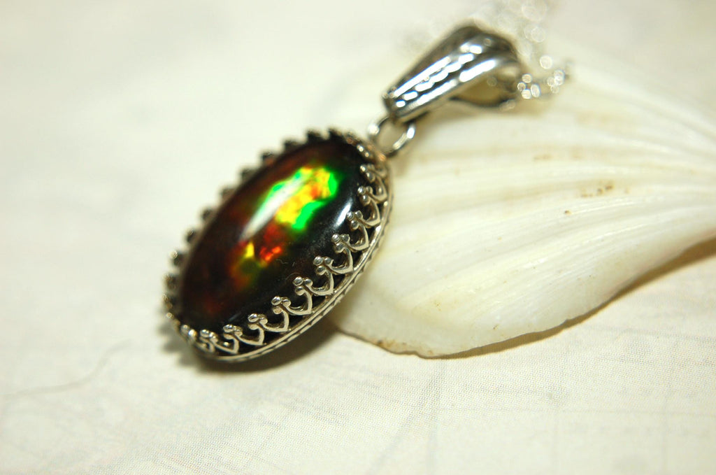Ammolite pendant looks like hot coals.Lovely Mysterious accessory.Rich reds,copper and gold alternate.Sterling silver setting.022616