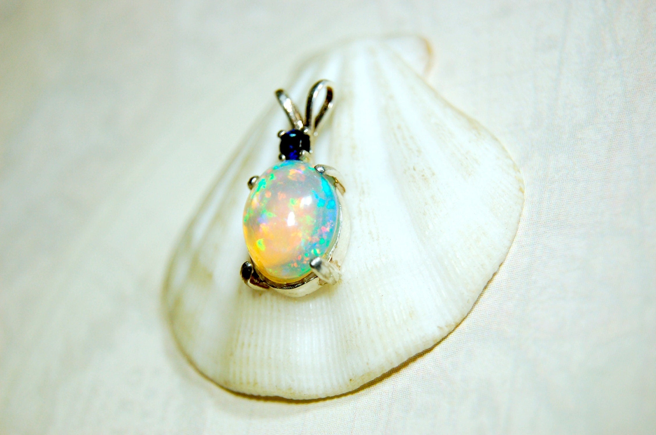 Natural opal pendant with blue sapphire.Good quality with many colors.The perfect gift.Must see video for true colors.042114