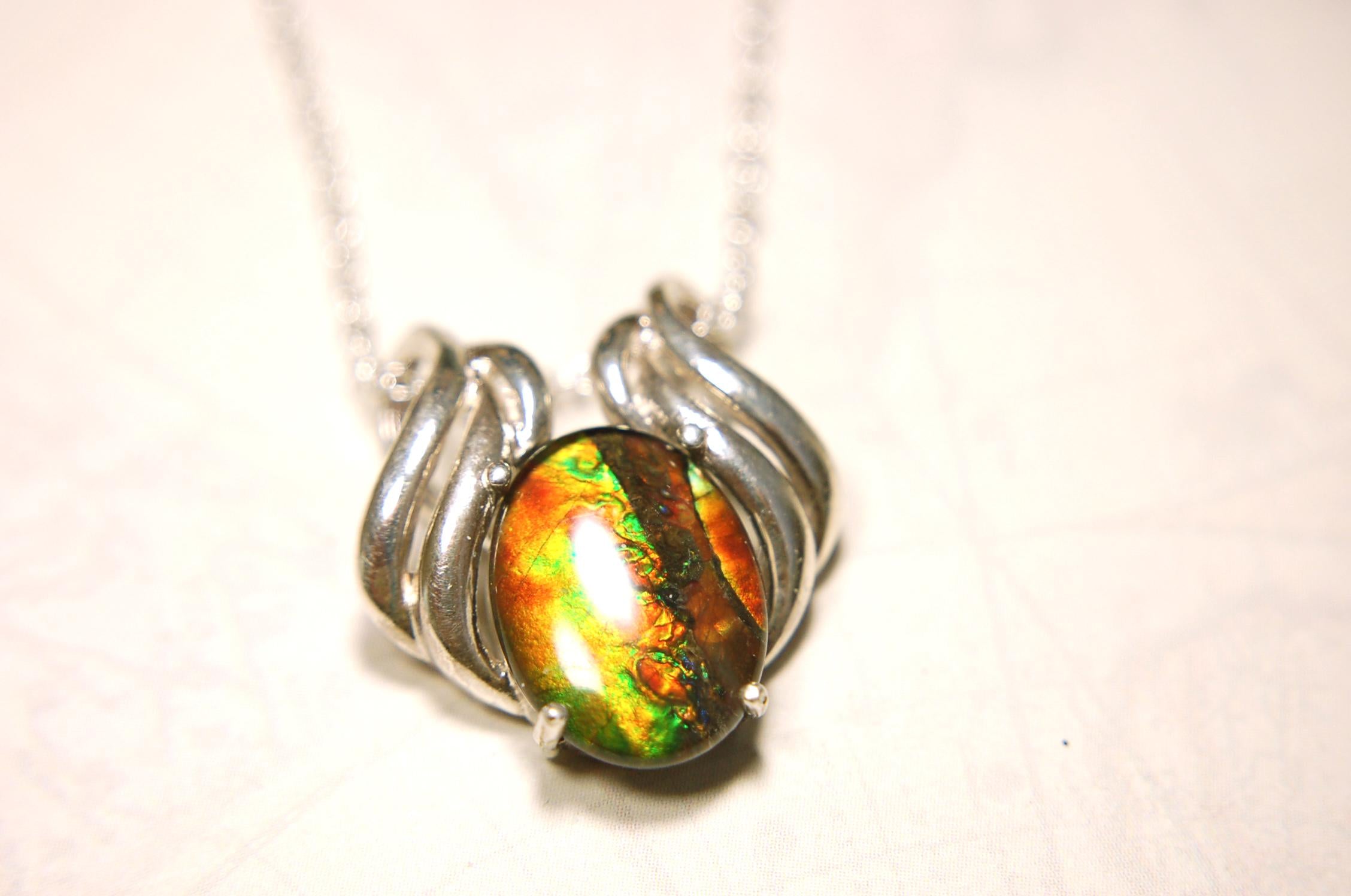 Ammolite pendant of unusual color pattern in a rare sterling silver setting.The green/copper colors are striking.022116