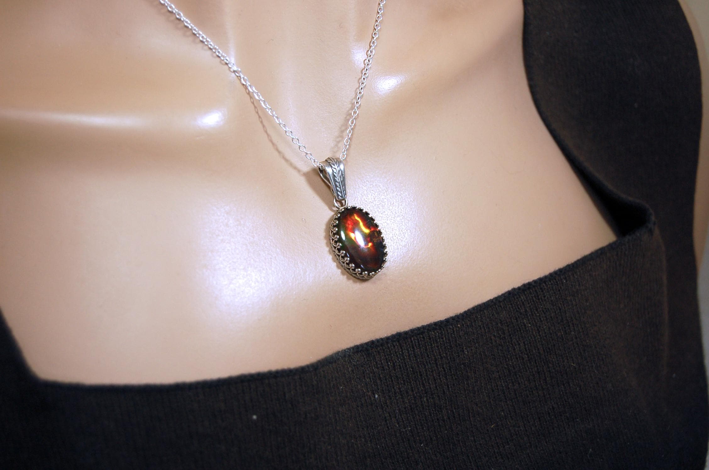 Ammolite pendant looks like hot coals.Lovely Mysterious accessory.Rich reds,copper and gold alternate.Sterling silver setting.022616