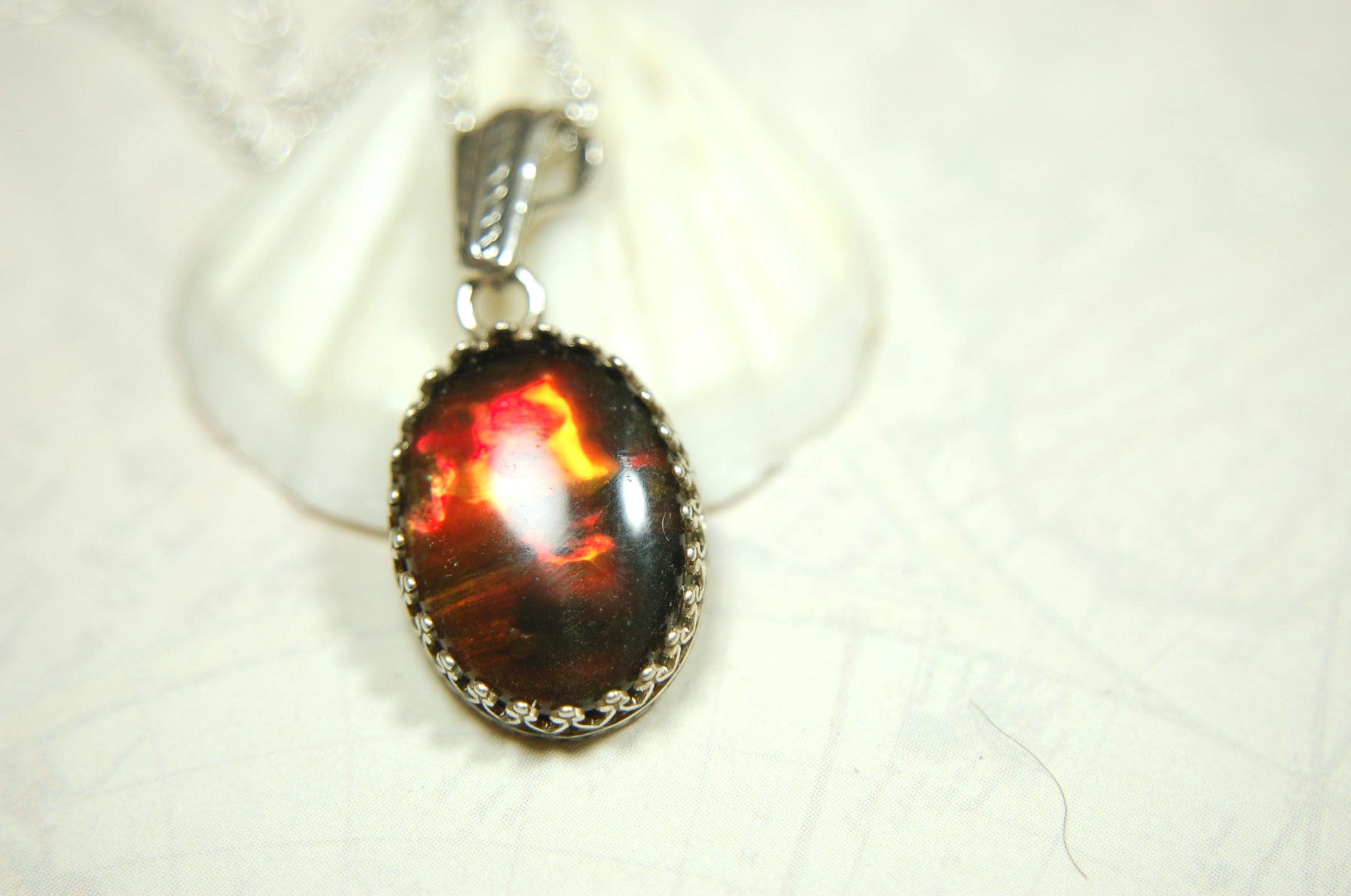 Ammolite pendant looks like hot coals.Lovely Mysterious accessory.Rich reds,copper and gold alternate.Sterling silver setting.022616