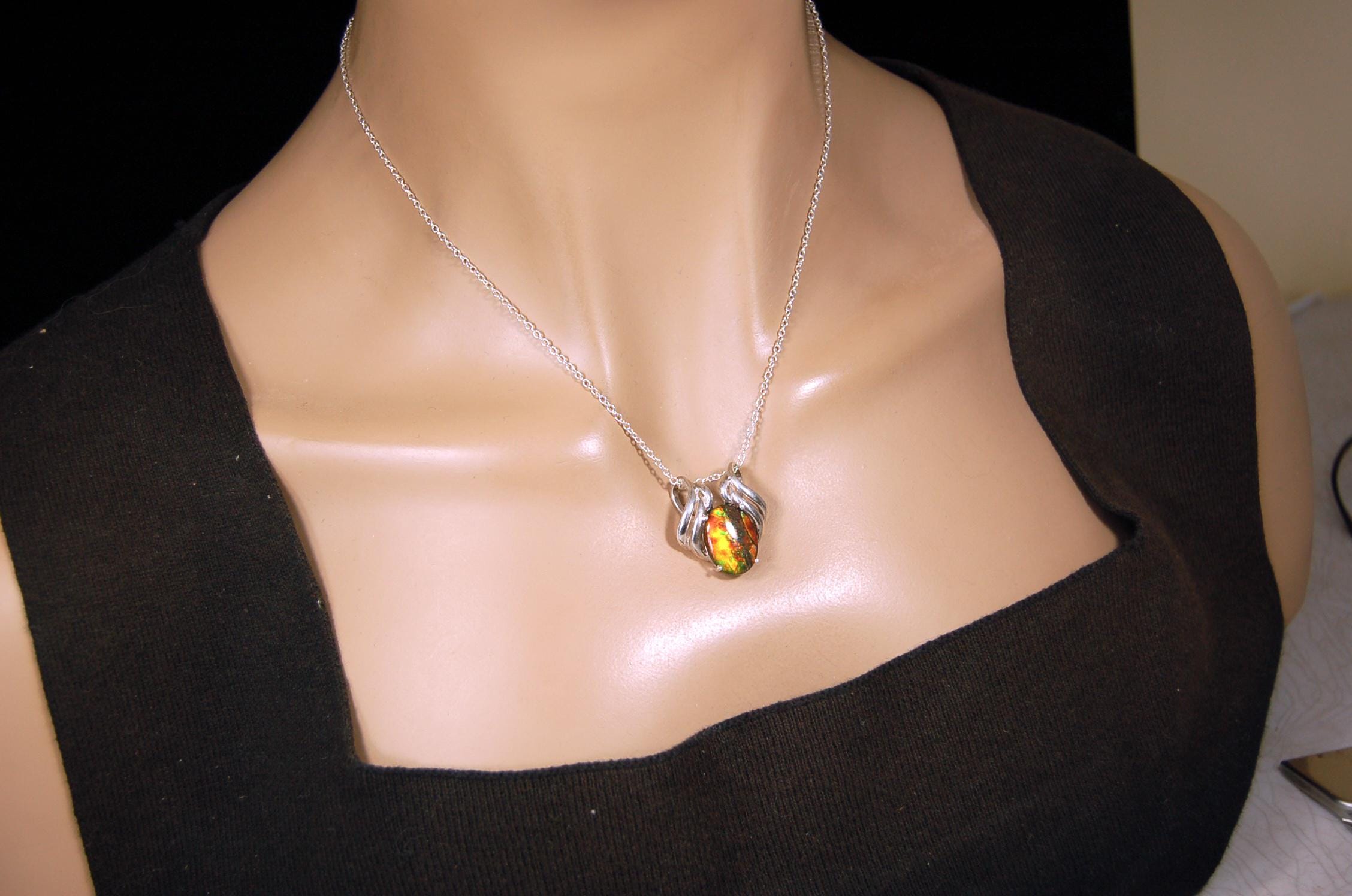Ammolite pendant of unusual color pattern in a rare sterling silver setting.The green/copper colors are striking.022116