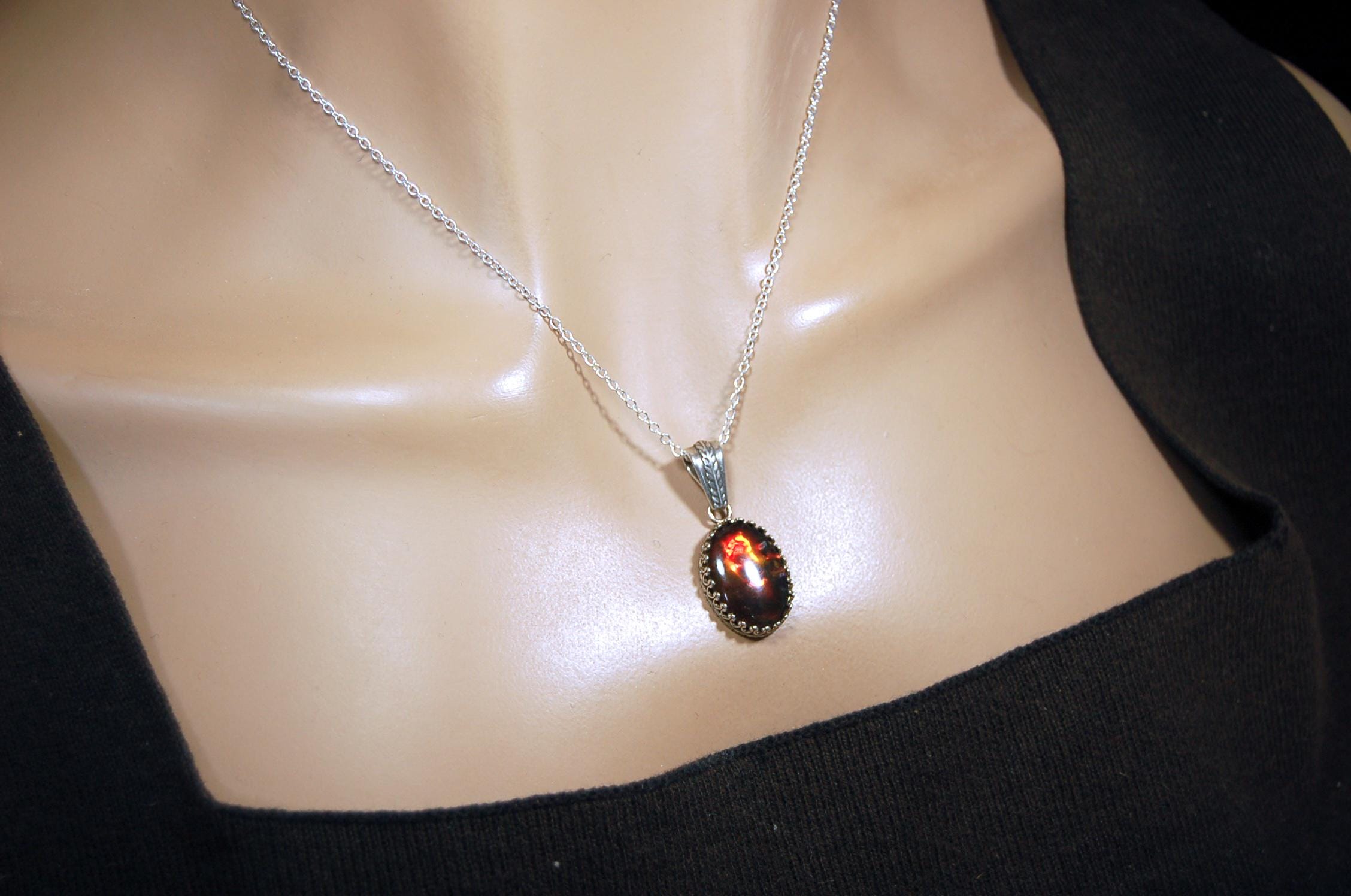 Ammolite pendant looks like hot coals.Lovely Mysterious accessory.Rich reds,copper and gold alternate.Sterling silver setting.022616