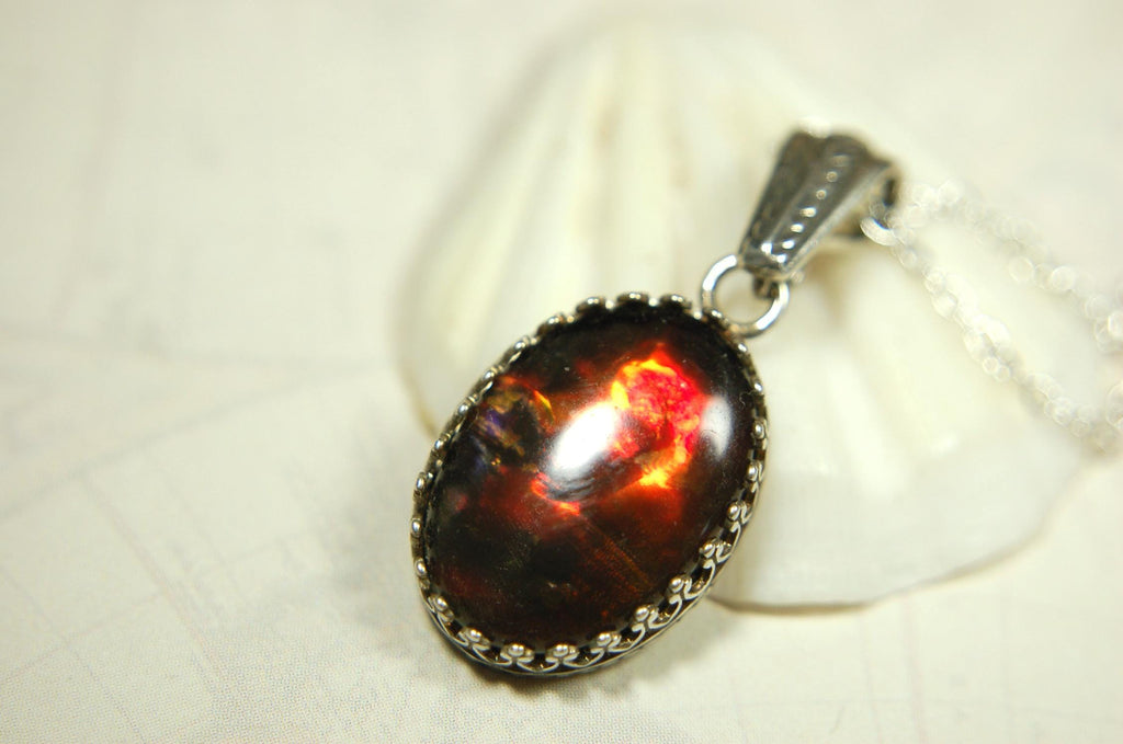 Ammolite pendant looks like hot coals.Lovely Mysterious accessory.Rich reds,copper and gold alternate.Sterling silver setting.022616