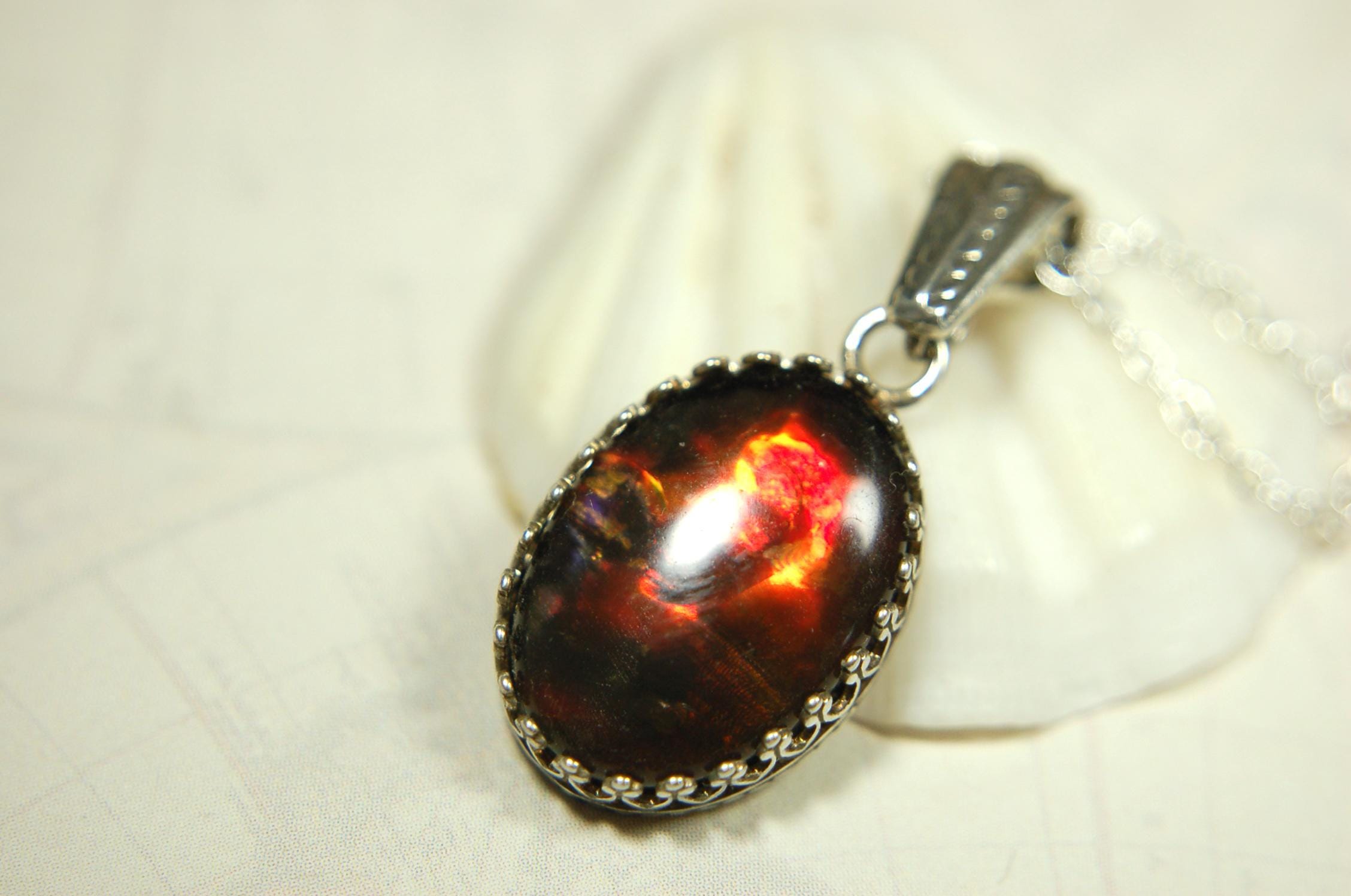 Ammolite pendant looks like hot coals.Lovely Mysterious accessory.Rich reds,copper and gold alternate.Sterling silver setting.022616