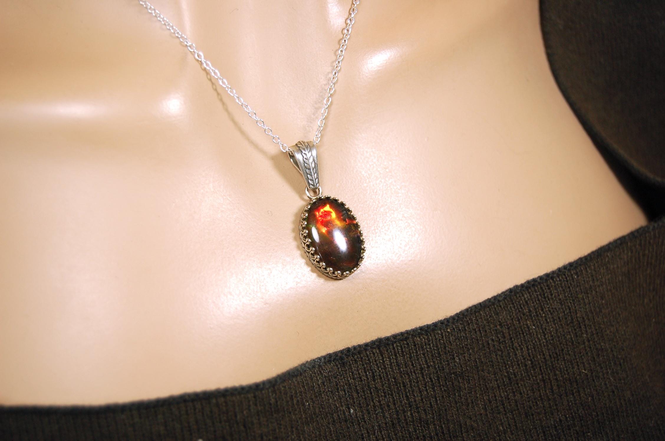 Ammolite pendant looks like hot coals.Lovely Mysterious accessory.Rich reds,copper and gold alternate.Sterling silver setting.022616