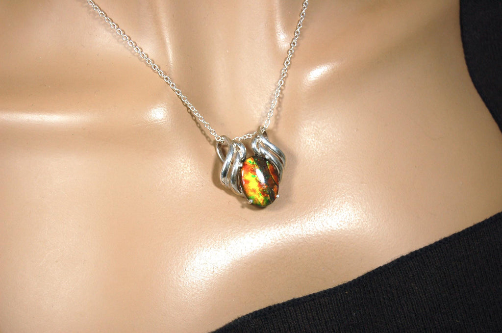 Ammolite pendant of unusual color pattern in a rare sterling silver setting.The green/copper colors are striking.022116
