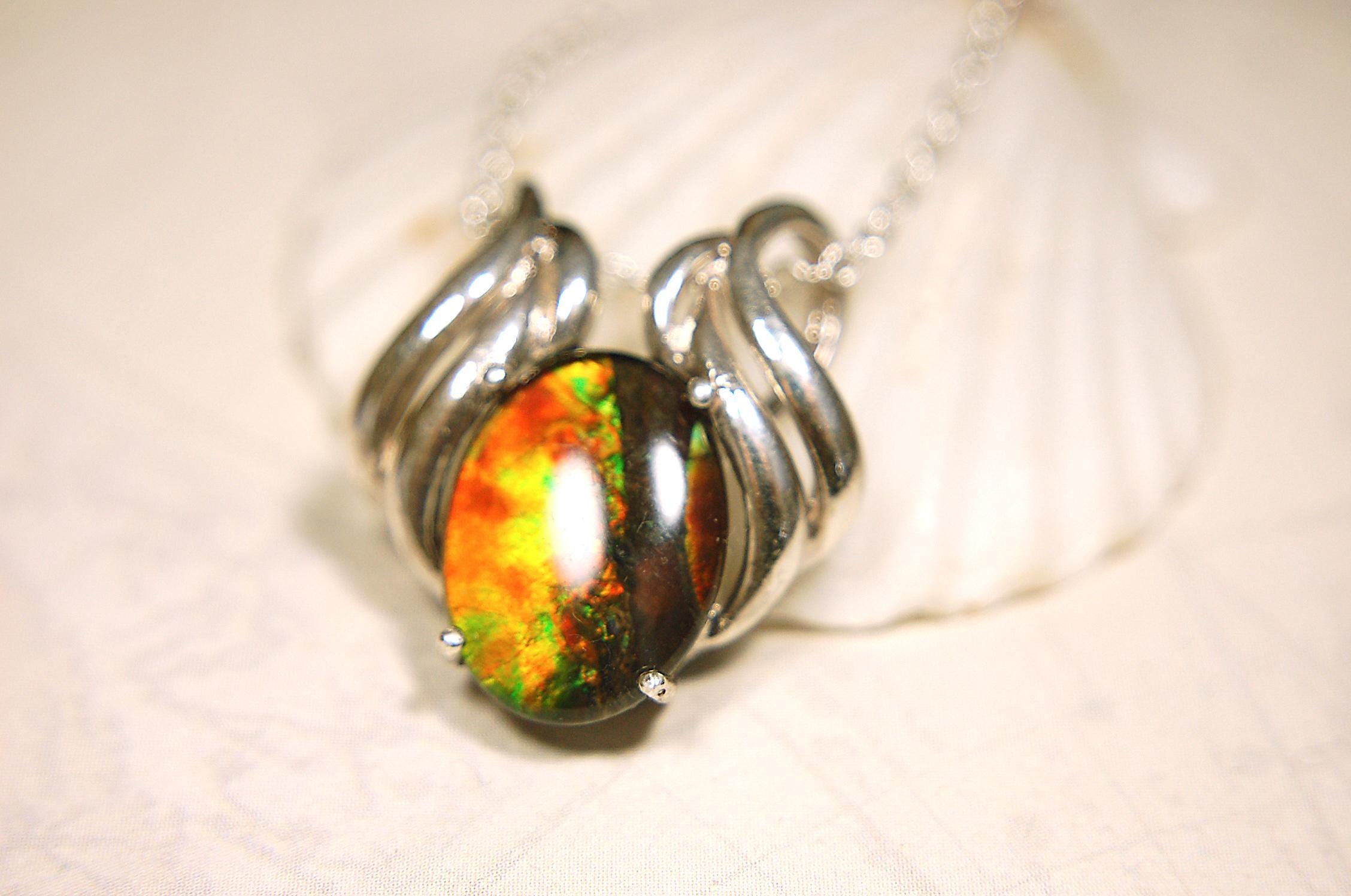Ammolite pendant of unusual color pattern in a rare sterling silver setting.The green/copper colors are striking.022116