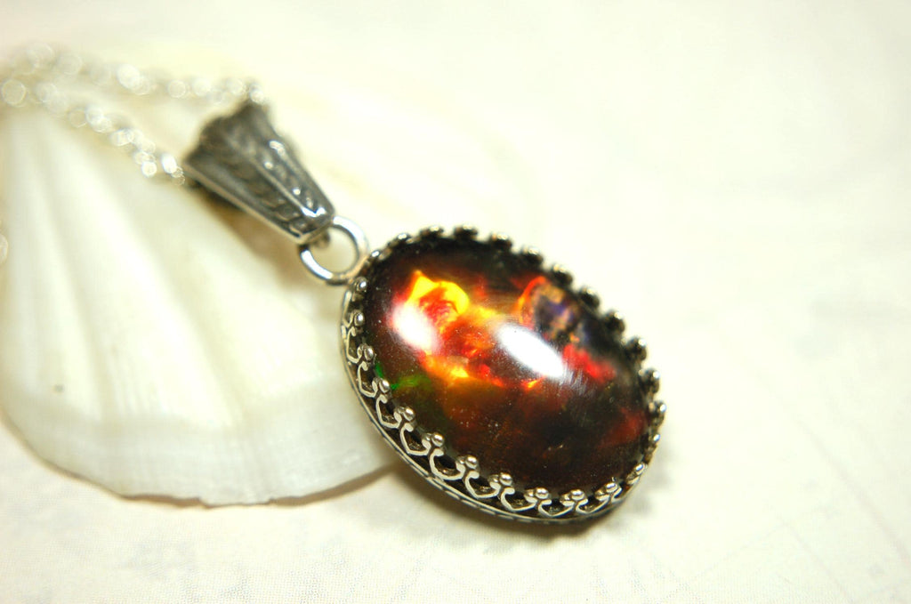 Ammolite pendant looks like hot coals.Lovely Mysterious accessory.Rich reds,copper and gold alternate.Sterling silver setting.022616