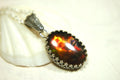 Ammolite pendant looks like hot coals.Lovely Mysterious accessory.Rich reds,copper and gold alternate.Sterling silver setting.022616