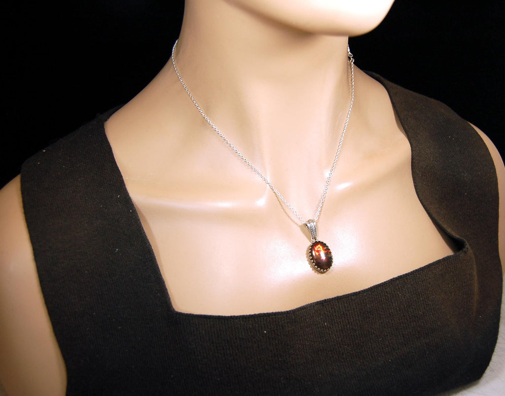 Ammolite pendant looks like hot coals.Lovely Mysterious accessory.Rich reds,copper and gold alternate.Sterling silver setting.022616