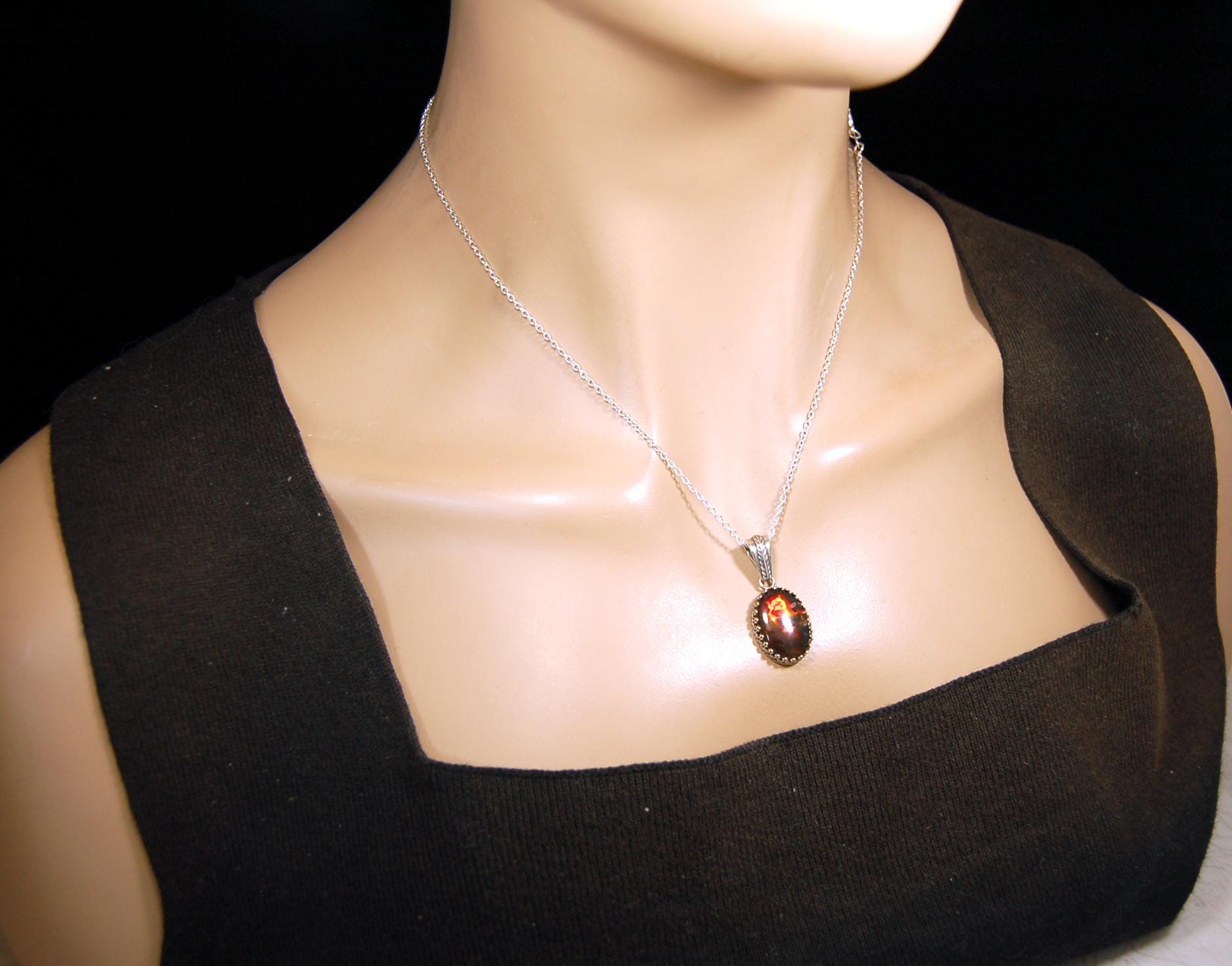 Ammolite pendant looks like hot coals.Lovely Mysterious accessory.Rich reds,copper and gold alternate.Sterling silver setting.022616