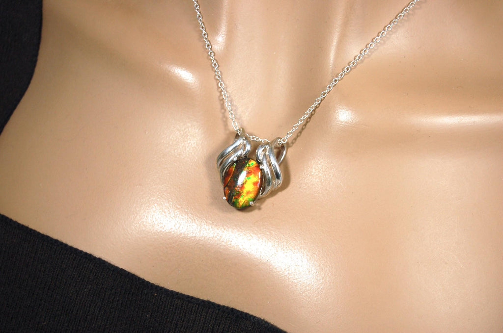 Ammolite pendant of unusual color pattern in a rare sterling silver setting.The green/copper colors are striking.022116