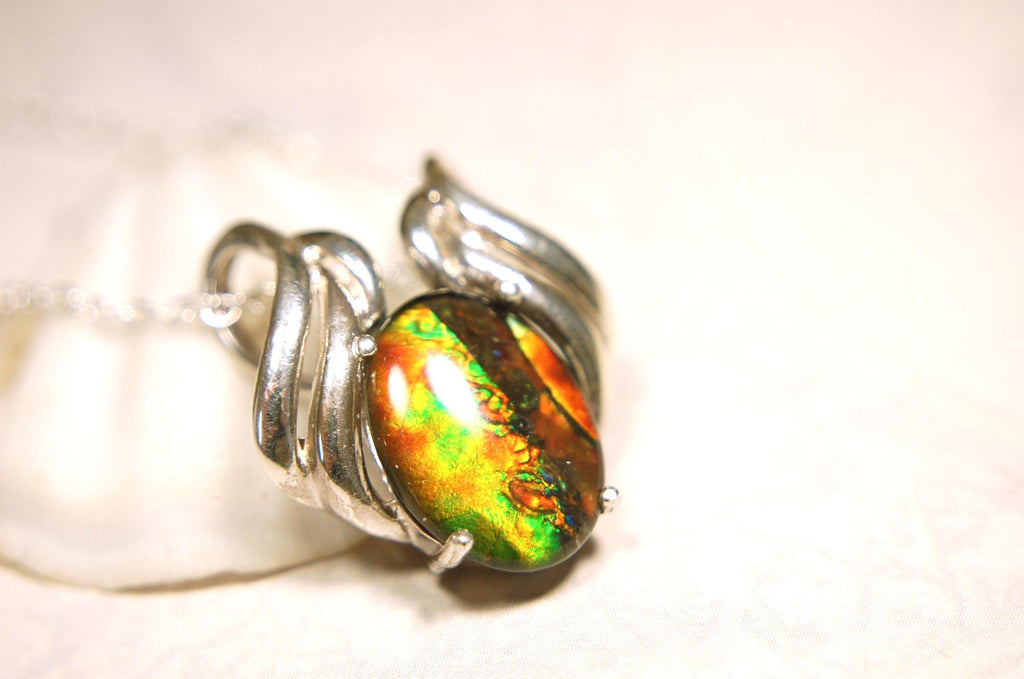 Ammolite pendant of unusual color pattern in a rare sterling silver setting.The green/copper colors are striking.022116
