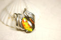 Ammolite pendant of unusual color pattern in a rare sterling silver setting.The green/copper colors are striking.022116
