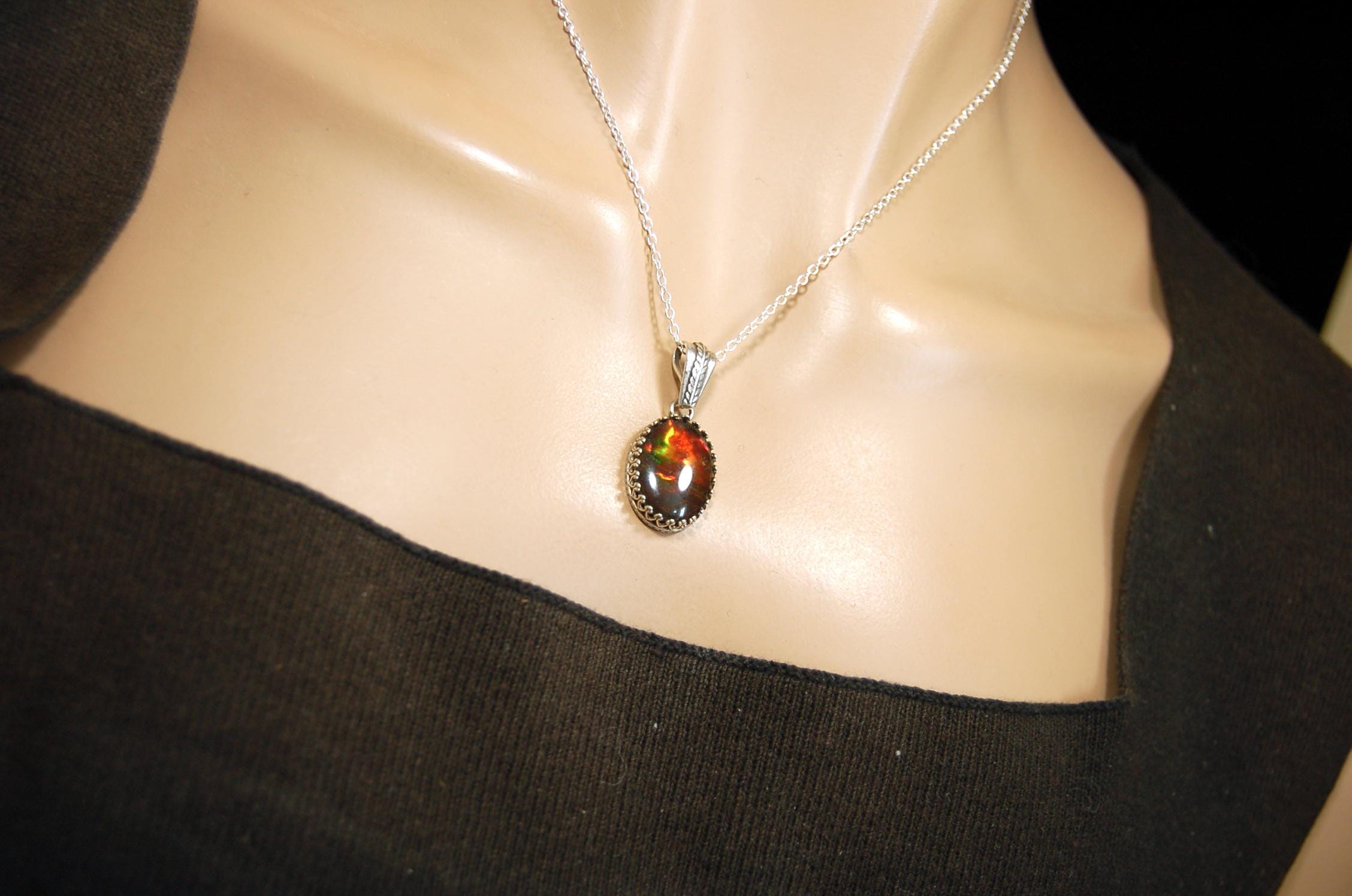 Ammolite pendant looks like hot coals.Lovely Mysterious accessory.Rich reds,copper and gold alternate.Sterling silver setting.022616